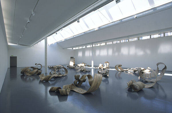 DCA Galleries during Richard Deacon's exhibition. There are large, curled, wooden sculptures on the gallery floors.