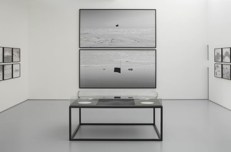 From Santiago Sierra's exhibition Black Flag. Large black-and-white images hanging on a wall show a black flag against a snowy landscape.