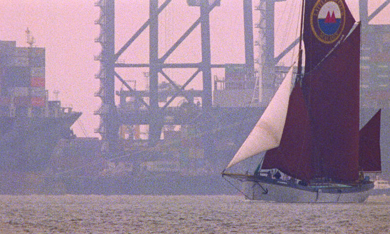 A boat sails next to an oil rig.