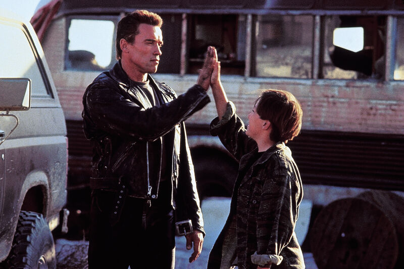 A tall man and a teenage boy awkwardly high five