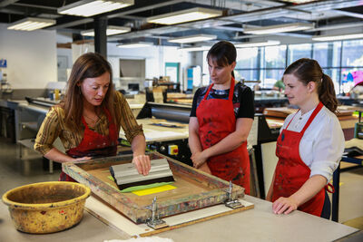 Person demonstrating screen printing to other people