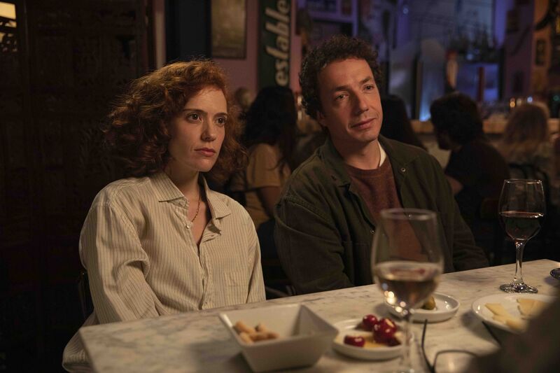 A man and a woman sit next to each other at a dinner table.