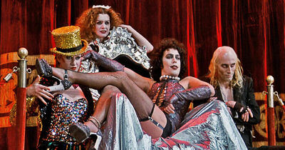 Four people stand around a thrown dressing in costumes