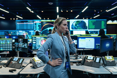 A woman in a blue suit talks on the telephone in a a government nuclear control centre