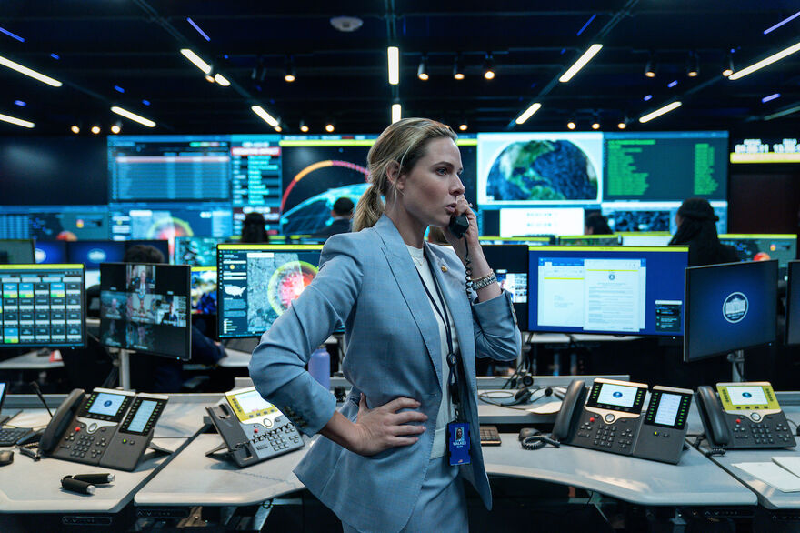 A woman in a blue suit talks on the telephone in a a government nuclear control centre