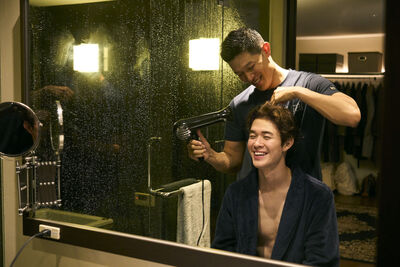 A man blow dries another man's hair
