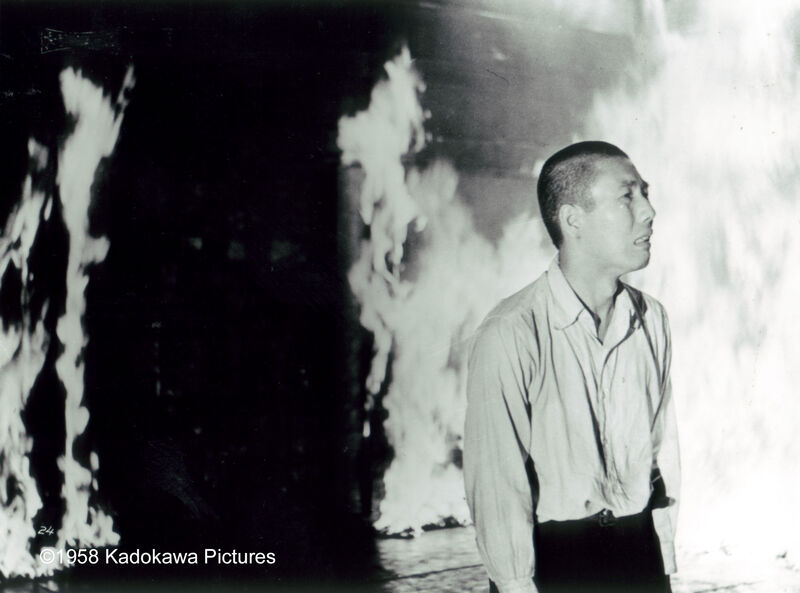 A black and white photograph shows a distressed man standing next to a burning building