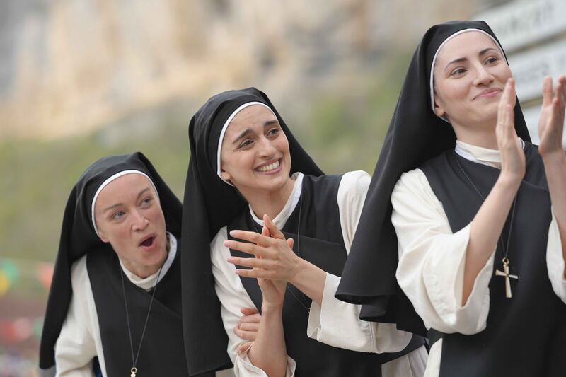 Three young nuns clap and cheer.