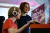 A person smiles while watching a child playing a game at Drop in and Play