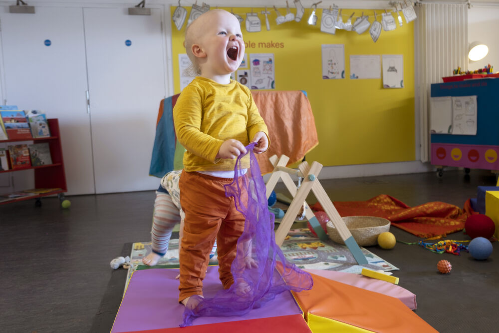 Child smiling while holding a piece of colourful fabric