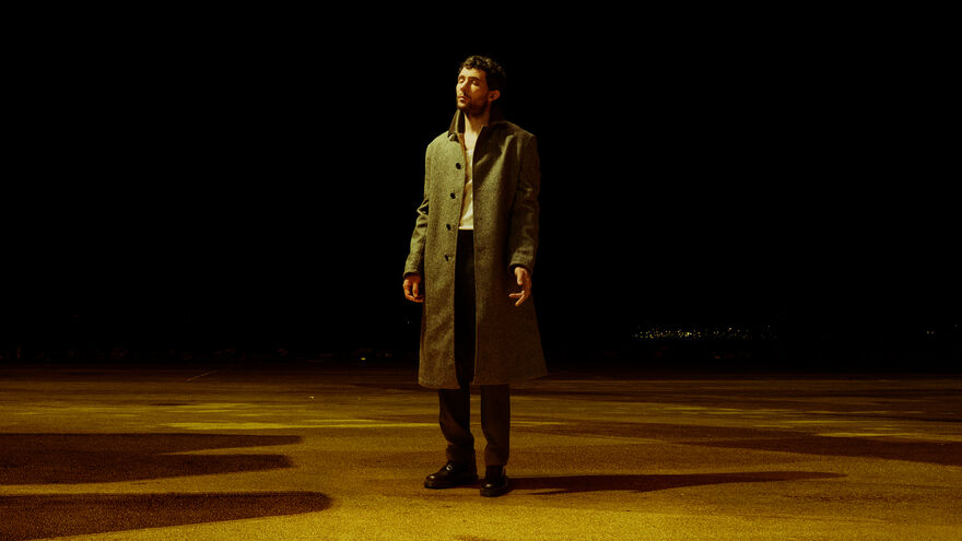 A young man stands with his eyes closed in the spotlight