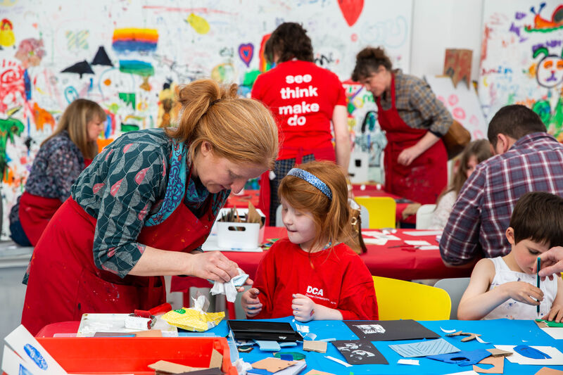 Families at tables in Gallery 1 using art materials to make together