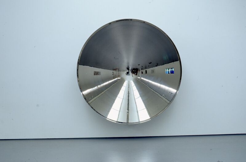 A large, circular mirror hangs on a white wall.