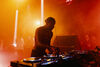 A man djing with a hazy smoke filled background of people dancing 