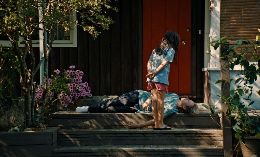 A girl stands over a teenage boy, lying on the ground.