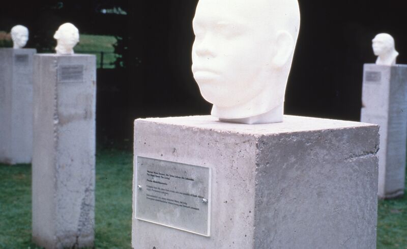 White heads made out of ceramic sit on top of concrete plinths.