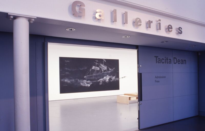 DCA Galleries seen from the outside - silver lettering above the door says 'Galleries', and on the inside we can see a large black canvas with a white sailboat drawn on it in chalk.