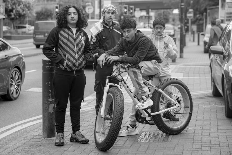 Three teen boys in the street with a bike