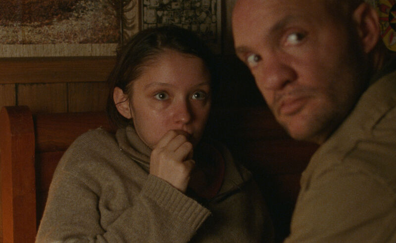 Girl looking worried as man sits in front of her looking over his shoulder