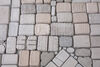 Close up of small cast brick-like objects laid on the floor in a grid. 