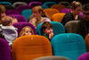 Children and their grown ups ready to watch a film in DCA's colourful cinema seats