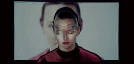 A young woman stands in front of projected image of herself