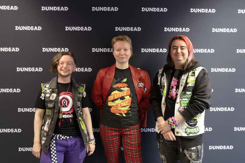three people posing in front of Dundead backdrop