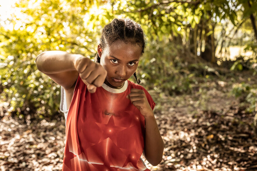 A girl looks intently at the camera fists raised in a punching motion