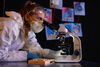 Person dressed in protective clothing looking into a microscope