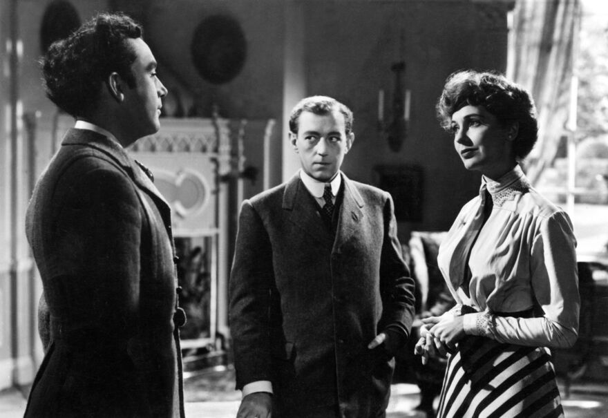 Two men and a woman stand in an elegant room in a still from Kind Hearts and Coronets