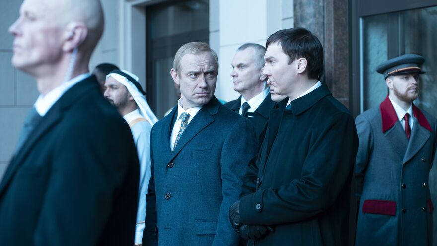 Russian politicians stand sternly in front of a building.