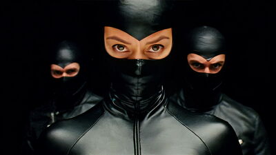 Three people dress in tight. black outfits that only show their eyes
