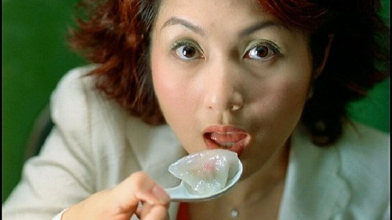 Woman eating a dumpling from a spoon