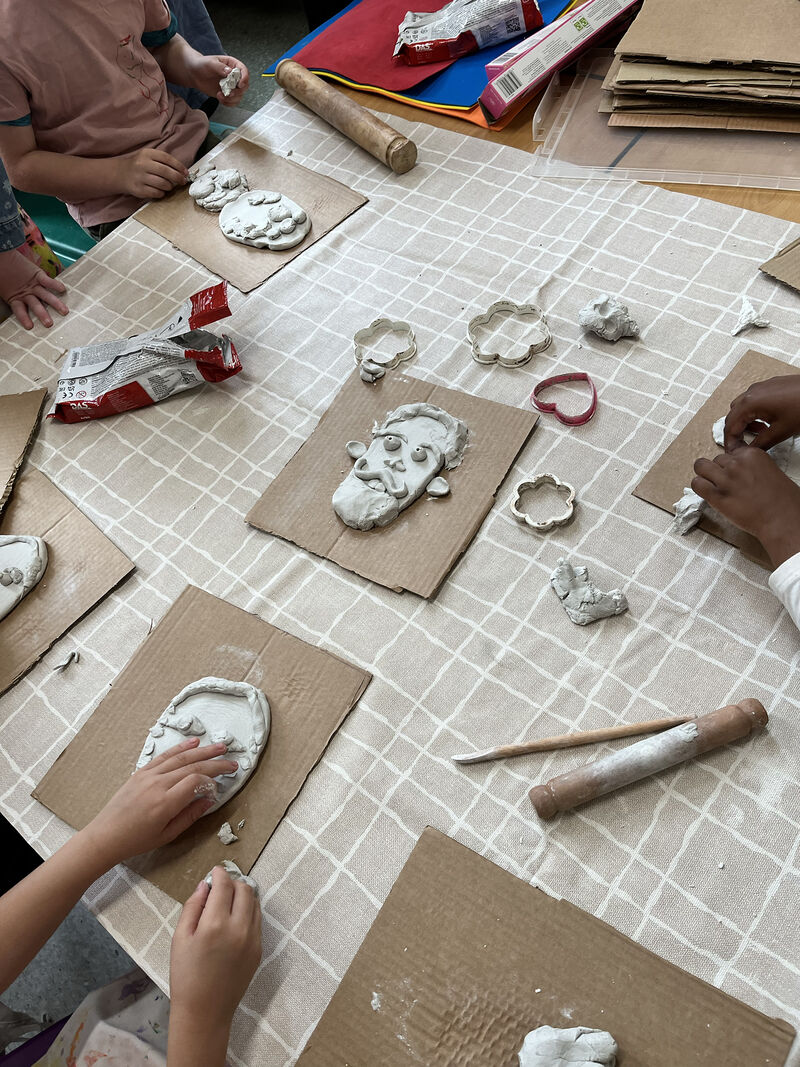 Children around a table making clay portraits