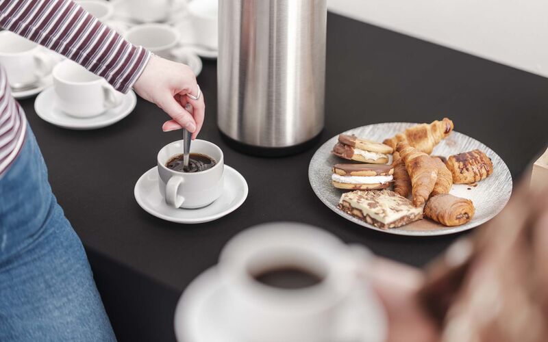 a platter of sweet treats and cups of coffee. 