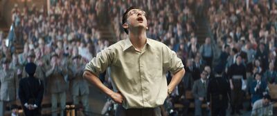 A man stands either his hands on his hips looking up at the sky while people applaud him