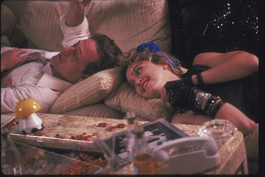A man and a woman lie on a sofa together, smiling.