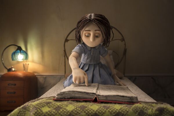 Animation still: a girl reads a book in bed by lamplight