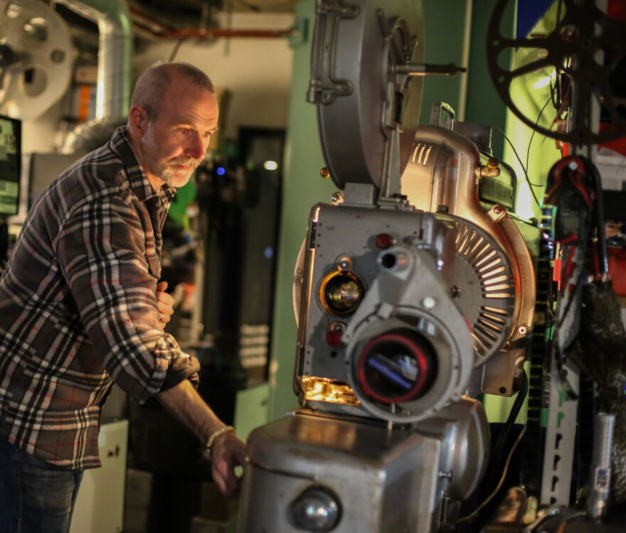 Projectionist adjusts a vintage projector in DCA projection booth