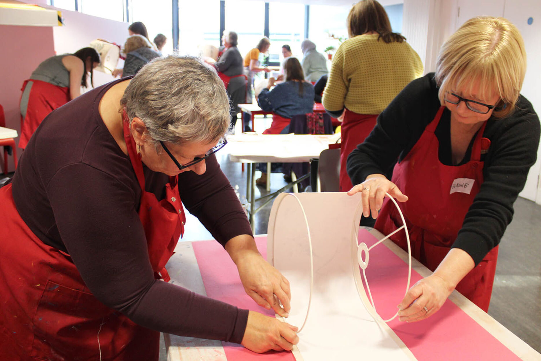 Two women make a lampshade at a Craft Sunday event.