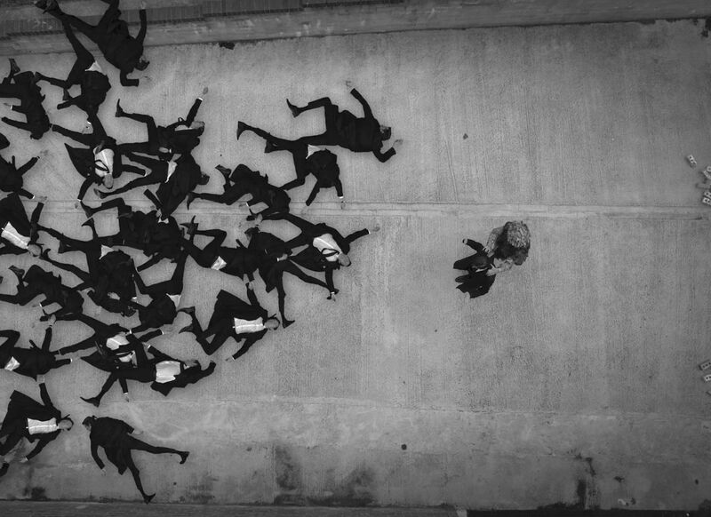 Black and white still from Bulk of people lying on the ground