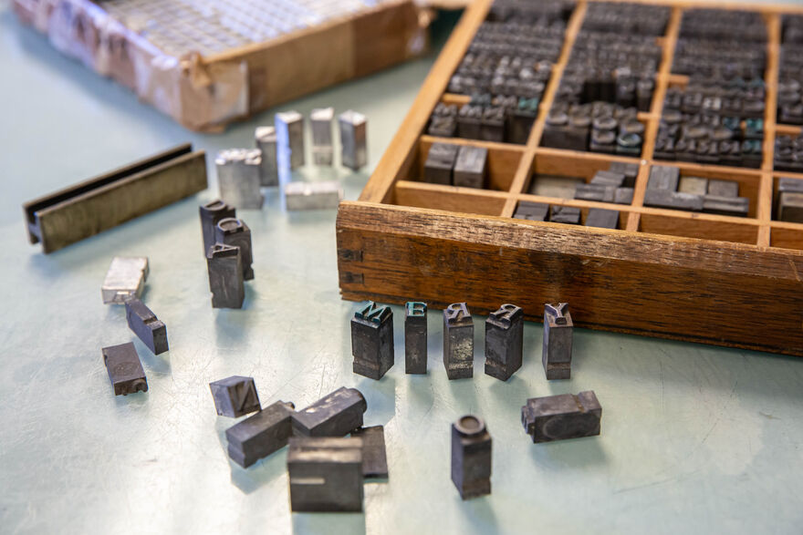 Letterpress type in box with letters laid out beside it to spell Merry