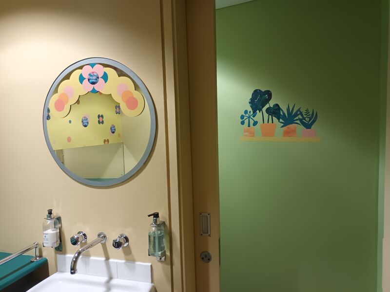 Our Infant Changing Space, decorated with paintings of flowers and green walls.