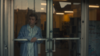 Woman standing lookking out a glass door