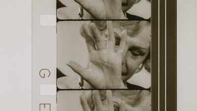 Leni Riefenstahl is shown on a film reel, holding a hand in front of her face.