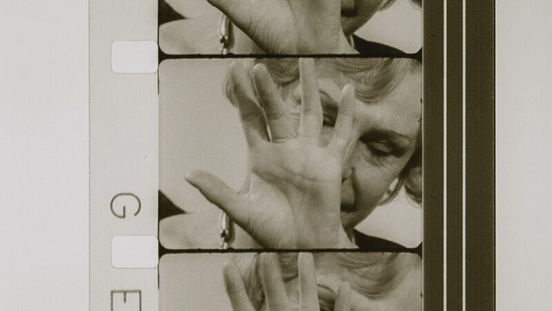 Leni Riefenstahl is shown on a film reel, holding a hand in front of her face.
