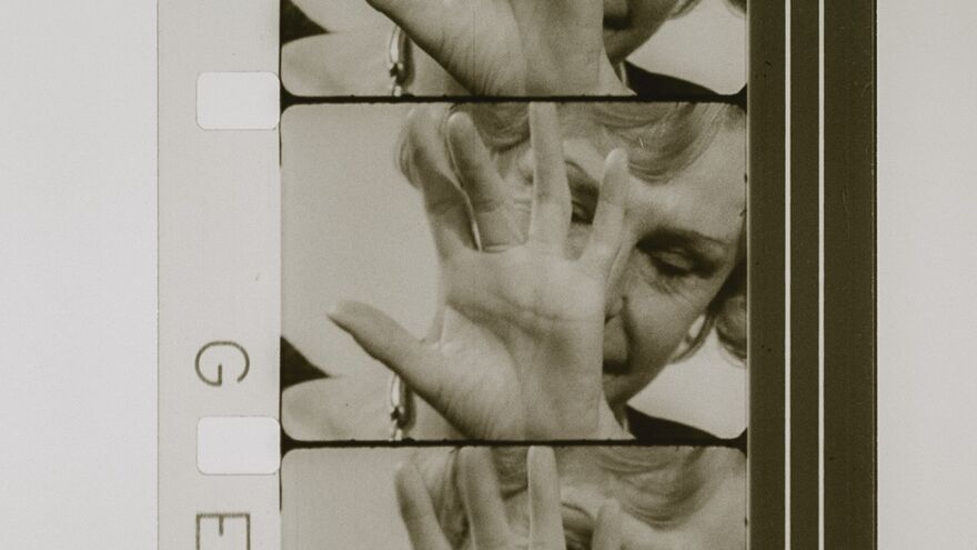 Leni Riefenstahl is shown on a film reel, holding a hand in front of her face.