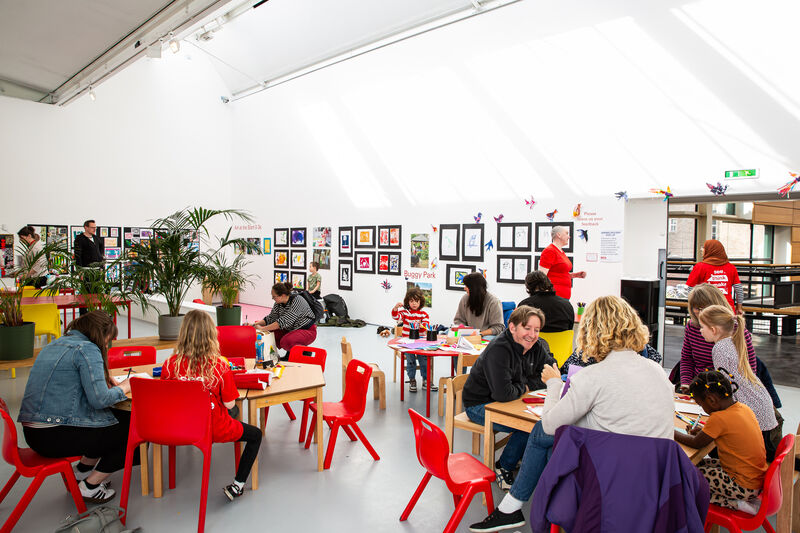 Families sitting at tables in Gallery 1 doing creative activities