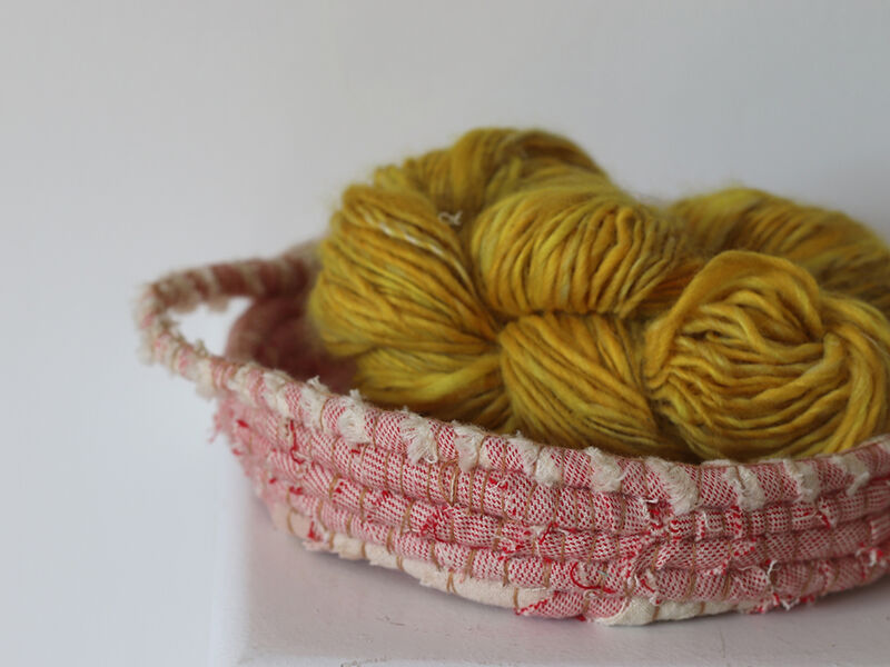 Basket made from red and white fabric, holding yellow wool