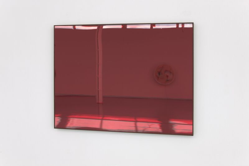 A red reflective surface hangs on the wall at Nina Rhode's exhibition, showing the other half of the gallery.